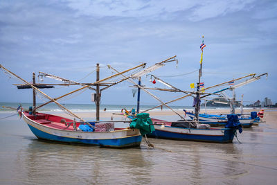 Fishing boats moored in sea against sky