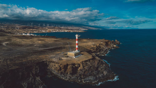 Lighthouse amidst sea and buildings against sky