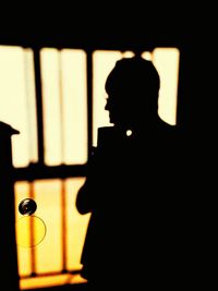 Close-up portrait of silhouette man standing against window
