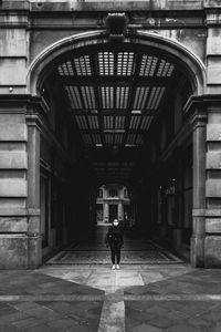 Rear view of girl walking on empty street amidst buildings in isolated city during covid-19.