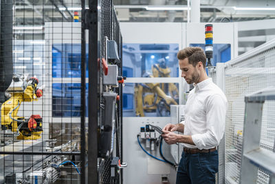 Businessman using tablet at a robot in a modern factory