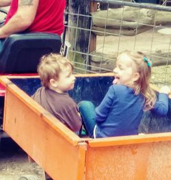 Rear view of siblings sitting outdoors