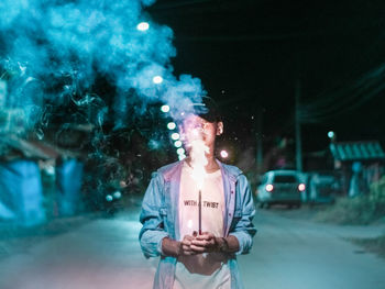 Young man smoking on street at night