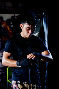 Young man wearing boxing gloves standing at gym