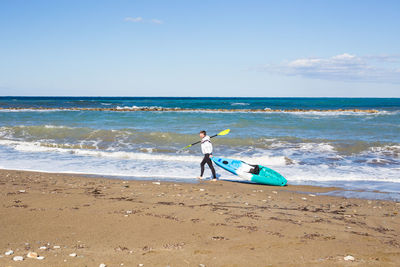 Rear view of man at beach against sky