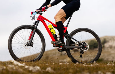 Low section of man riding bicycle on field