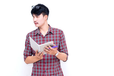 Young man looking away while standing against white background