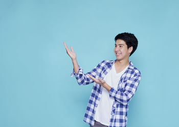 Young man standing against blue background