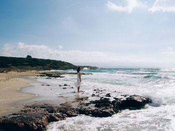 Woman standing in sea against sky