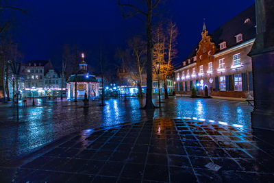 Illuminated street amidst buildings in city at night