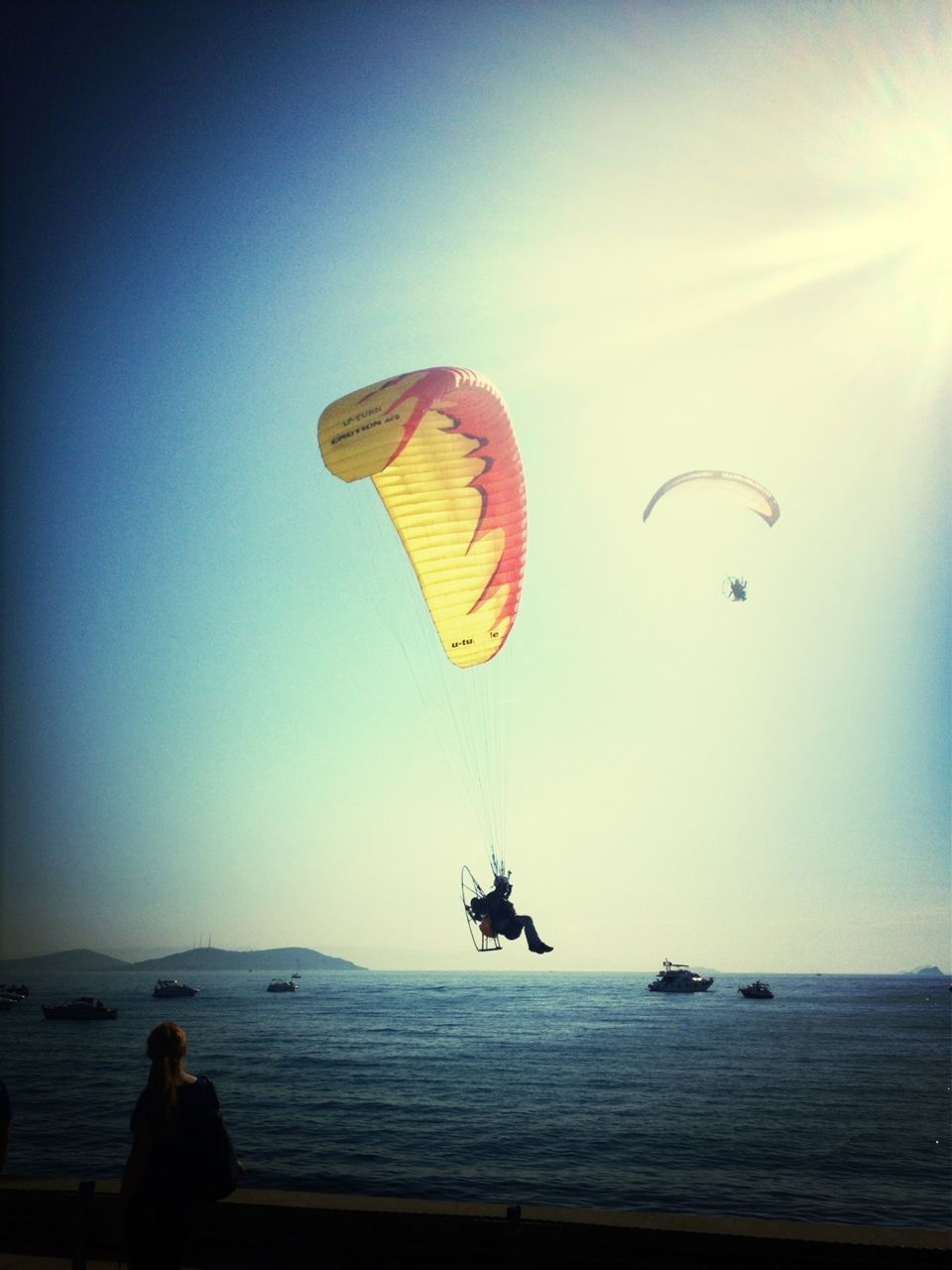 sea, parachute, leisure activity, flying, mid-air, beach, clear sky, extreme sports, paragliding, lifestyles, horizon over water, adventure, vacations, copy space, water, sport, scenics, unrecognizable person