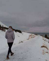 Rear view of woman walking on snow covered land