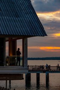 Rear view of man looking at sea against sky during sunset