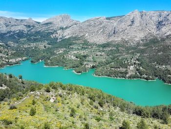 Scenic view of lake and mountains against clear blue sky