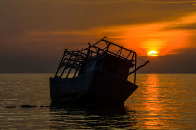 Silhouette boat in sea against sky during sunset