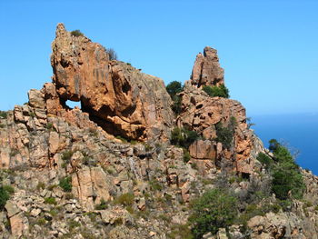 Rock formation on beach against clear blue sky