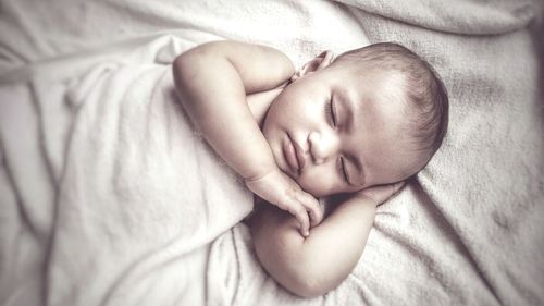 Close-up of baby sleeping on bed