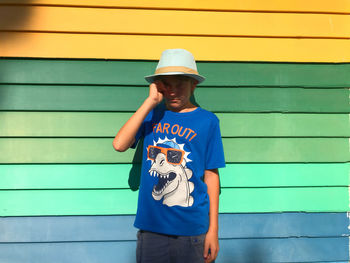 Full length of teenage boy standing against multicolored wall