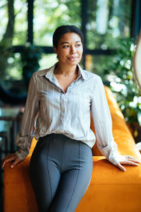 Portrait of young woman sitting on sofa at park