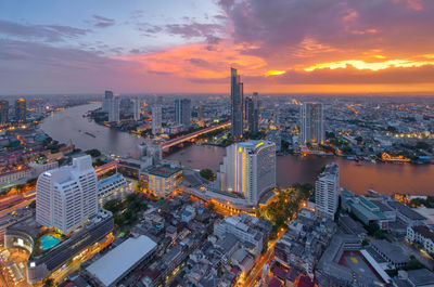 Illuminated cityscape against sky during sunset