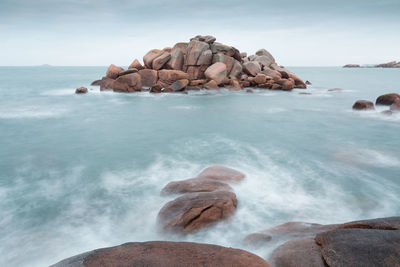 Rocks on sea shore against sky