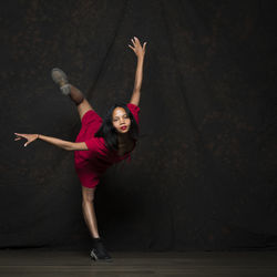 Full length of woman dancing on stage against black background