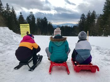 Rear view of people sitting on snowy field