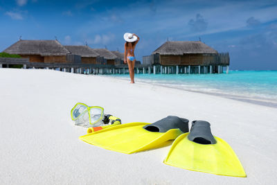 Close-up of diving flippers and snorkel with woman on shore at beach