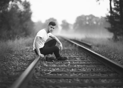 Side view of man sitting on railroad track