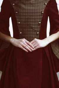 Female hands against the vintage dark red elegant dress