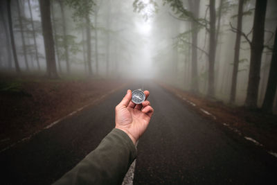 Man holding umbrella on road in forest