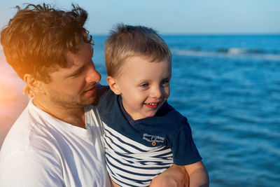 Close-up of father looking at son while standing at beach