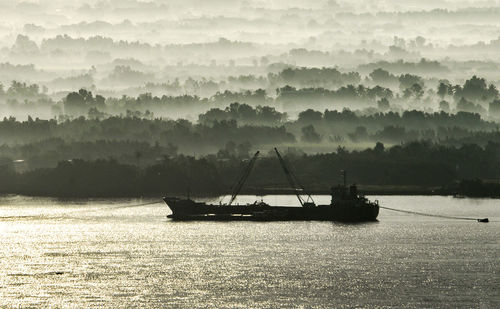 Ship moored at saigon river, with ground fog at the shore