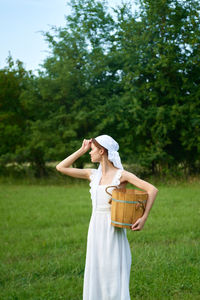 Midsection of woman holding hat while standing on field