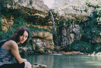 Woman next to a waterfall looking at camera