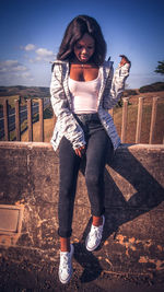 Portrait of a young woman standing against railing