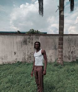 Full length portrait of young man standing on land against sky