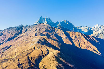 Scenic view of snowcapped mountains against clear blue sky