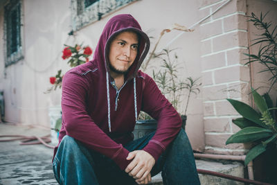 Portrait of young man standing against wall