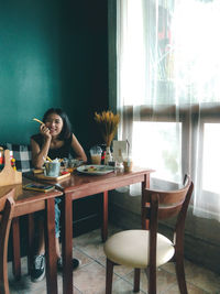 Young woman sitting on table at home