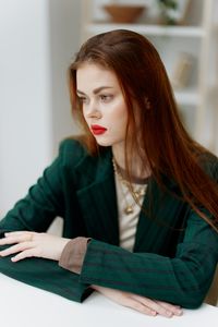 Portrait of young woman standing against wall