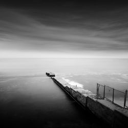 Pier amidst sea against cloudy sky