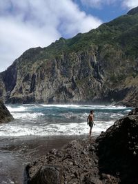 Shirtless man standing at beach against mountain