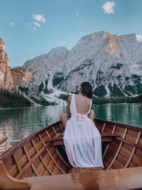 Rear view of woman looking at lake against mountain range