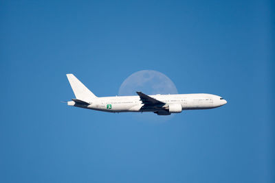 Low angle view of airplane flying against clear blue sky