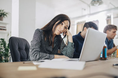 Tired business professional looking at laptop while sitting at desk in creative office