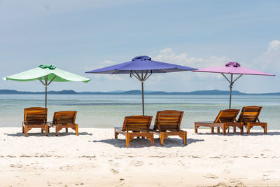 Deck chairs on beach against sky