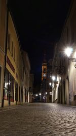 Illuminated street amidst buildings at night