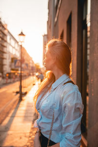 Side view of young woman standing on footpath