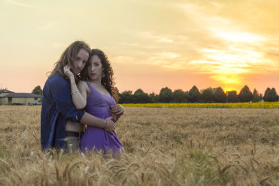 Happy woman standing on field against sky during sunset